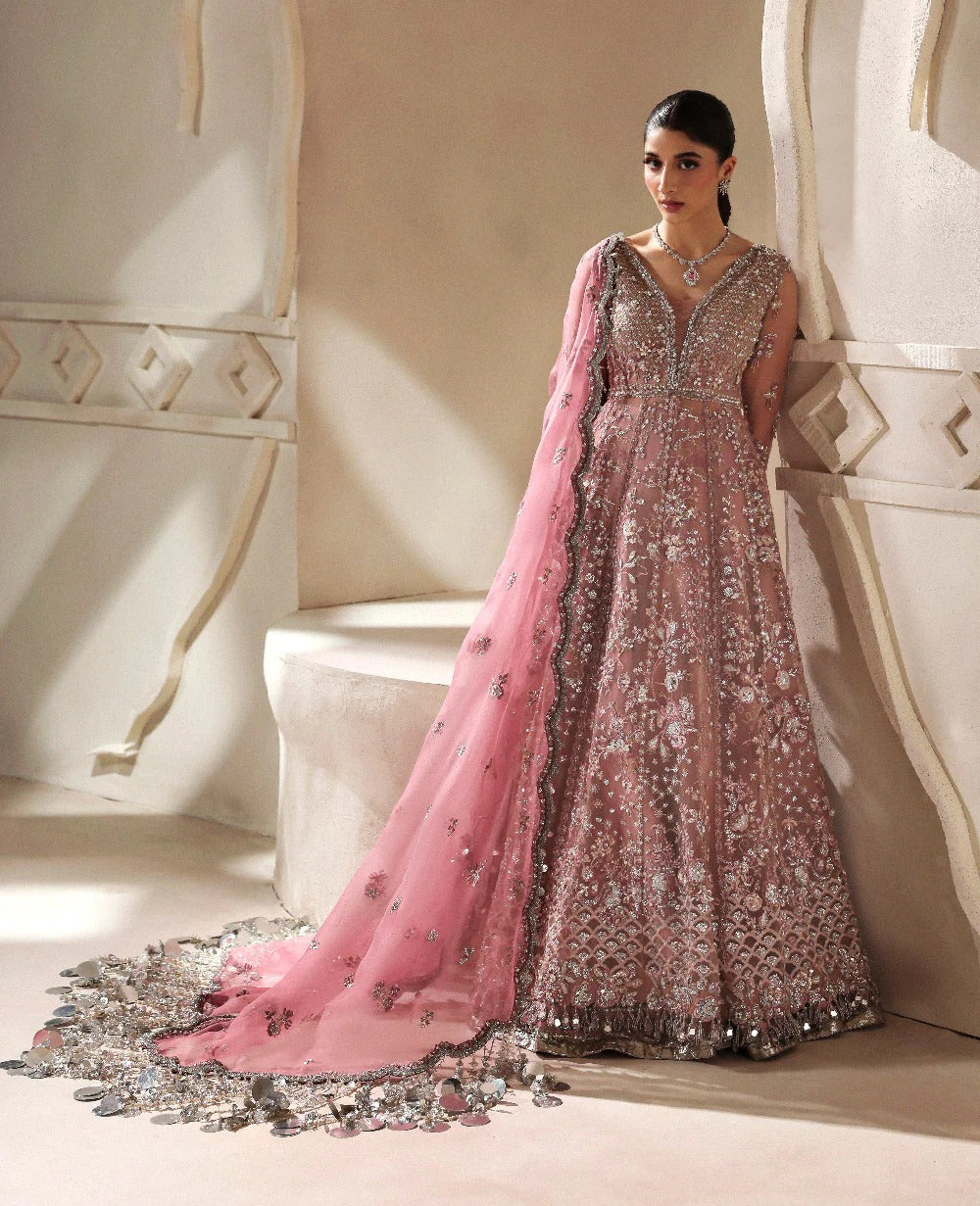 Woman in an ornate pink and silver dress with a matching dupatta in a decorative setting.
