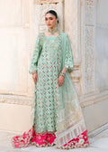 A woman models a mint green and pink heavily embroidered traditional outfit with a matching dupatta, set against a light-colored stone architectural background.