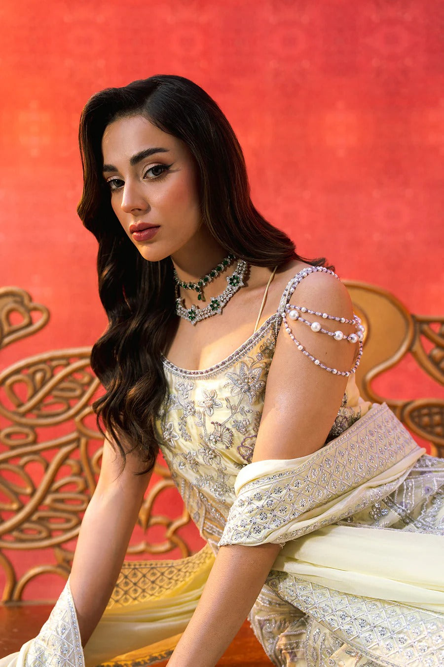 Woman in a traditional outfit with jewelry against a red background
