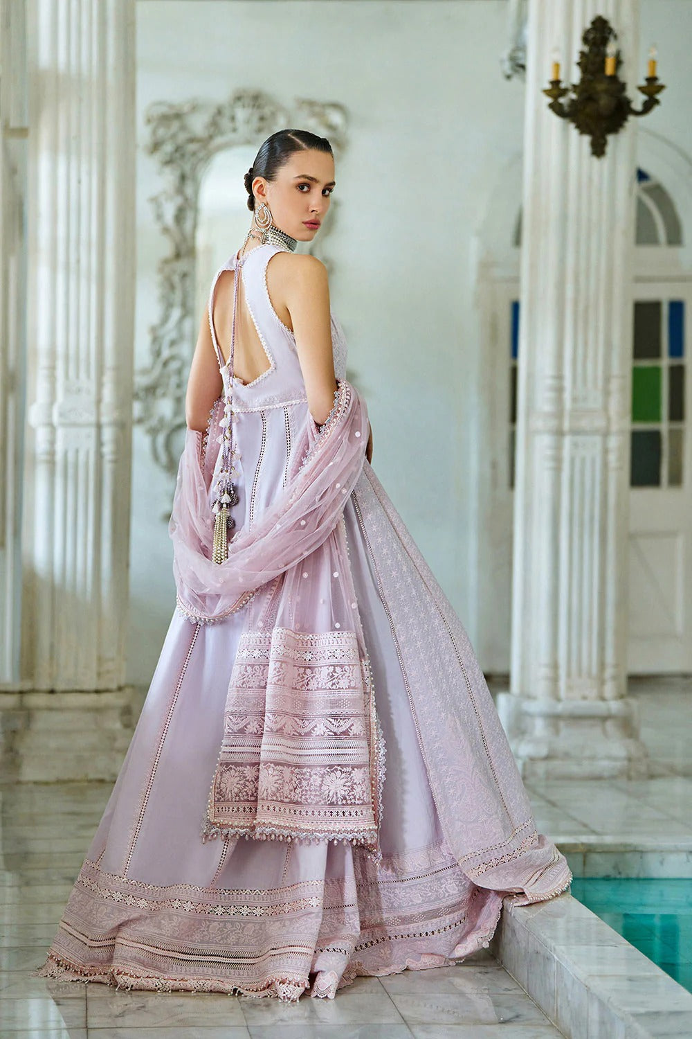 Woman in a pink traditional outfit standing in an elegant indoor setting.