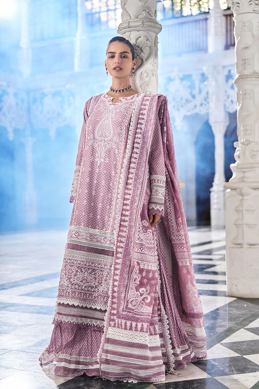 Woman in a pink traditional outfit standing in an elegant interior setting.