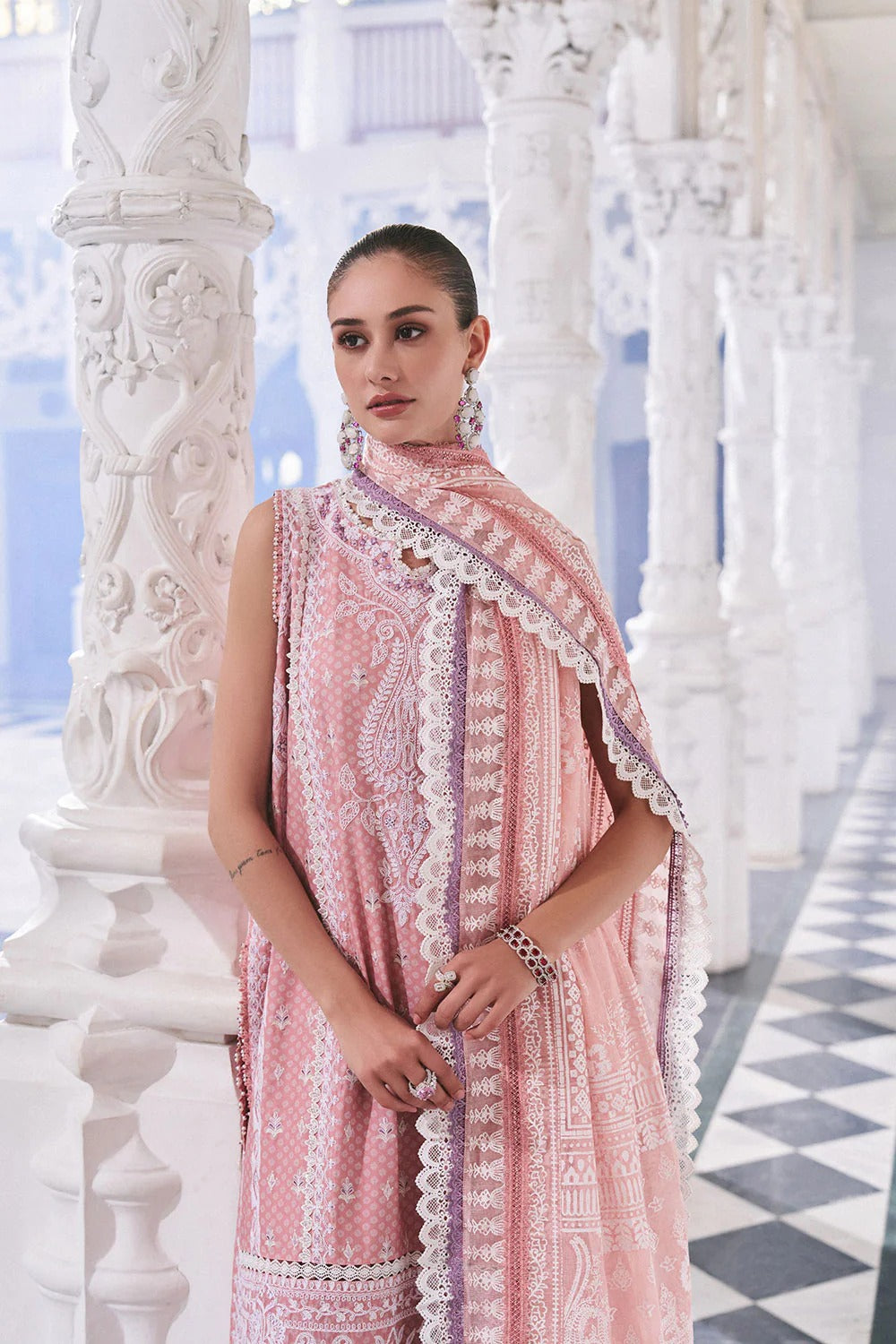 Woman wearing a pink dress with lace details in an ornate white interior setting