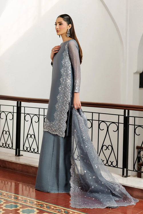 Woman in a gray traditional outfit with a matching dupatta in an elegant interior setting.