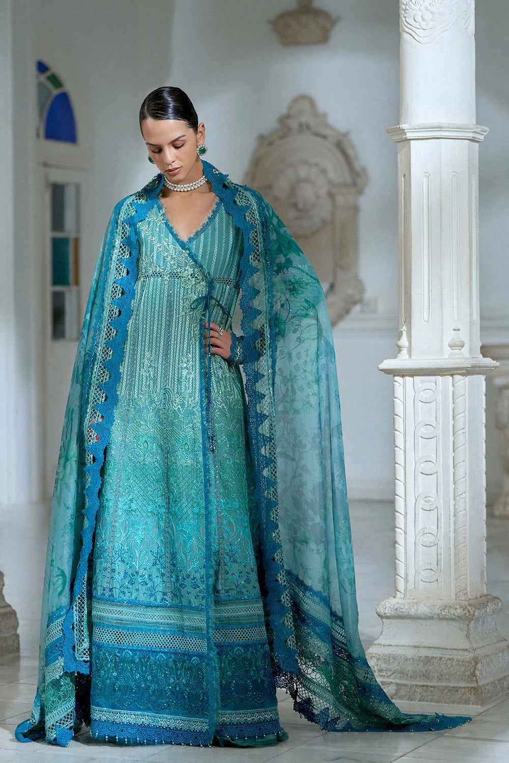 Woman in a blue and green dress with a matching shawl in an elegant indoor setting.