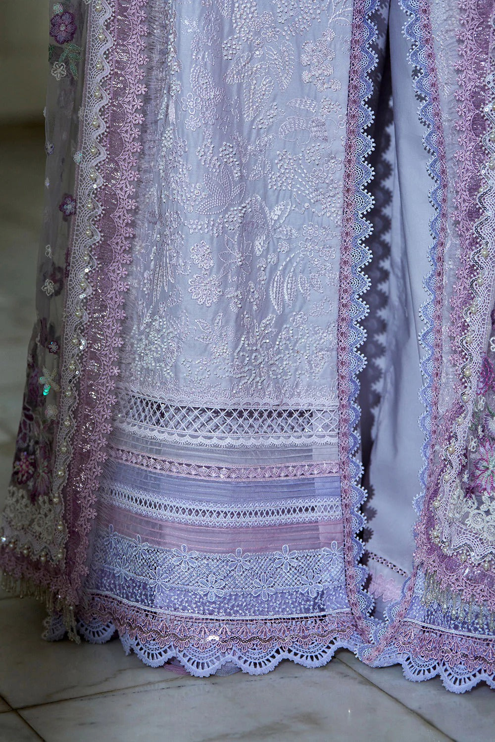 Close-up of a embroidered fabric with intricate patterns in pastel colors.
