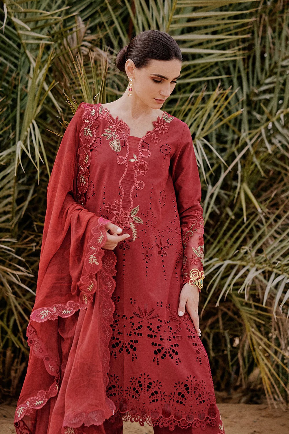 Woman in a red embroidered outfit standing against a natural background