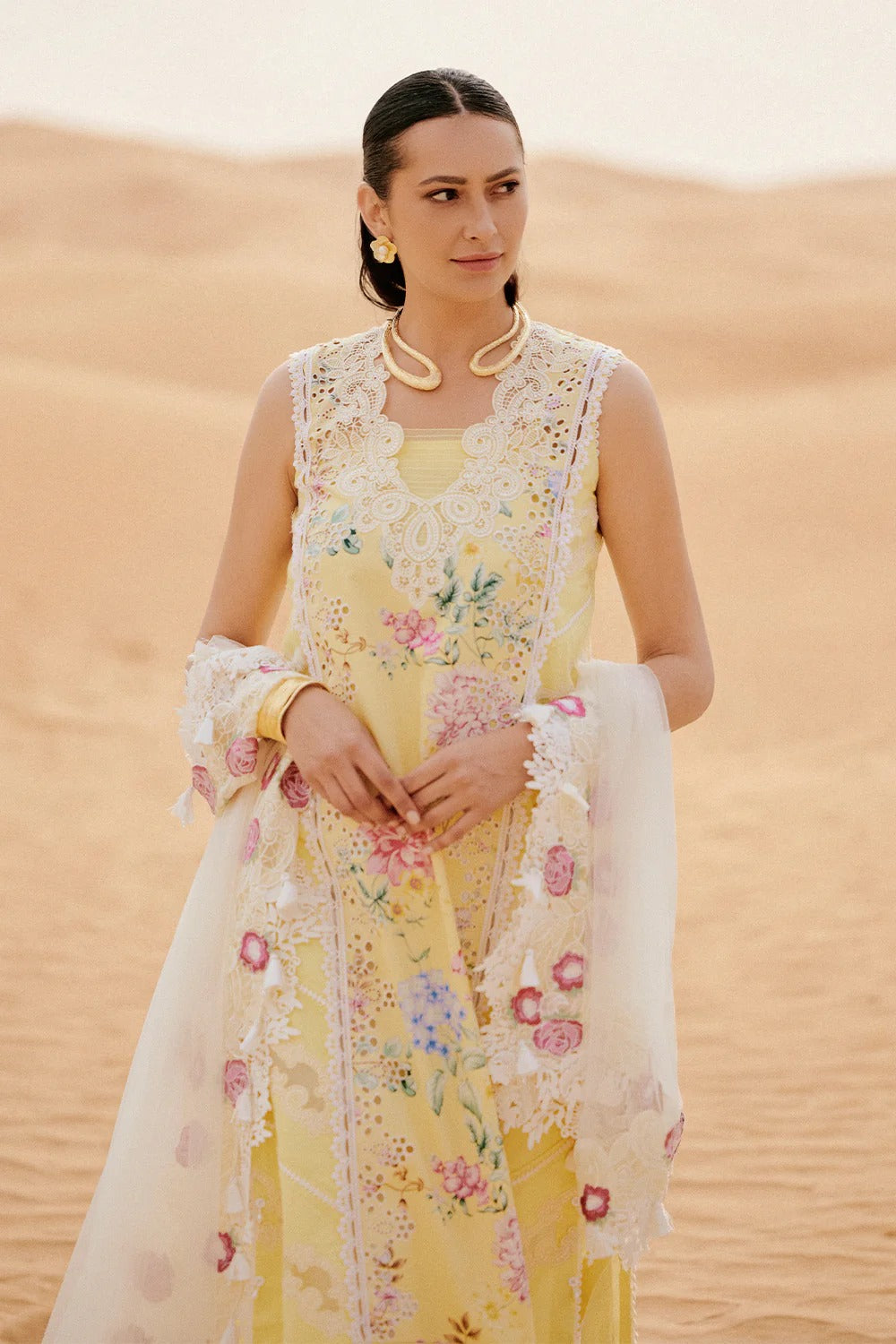 Woman in a yellow floral dress standing in a desert setting