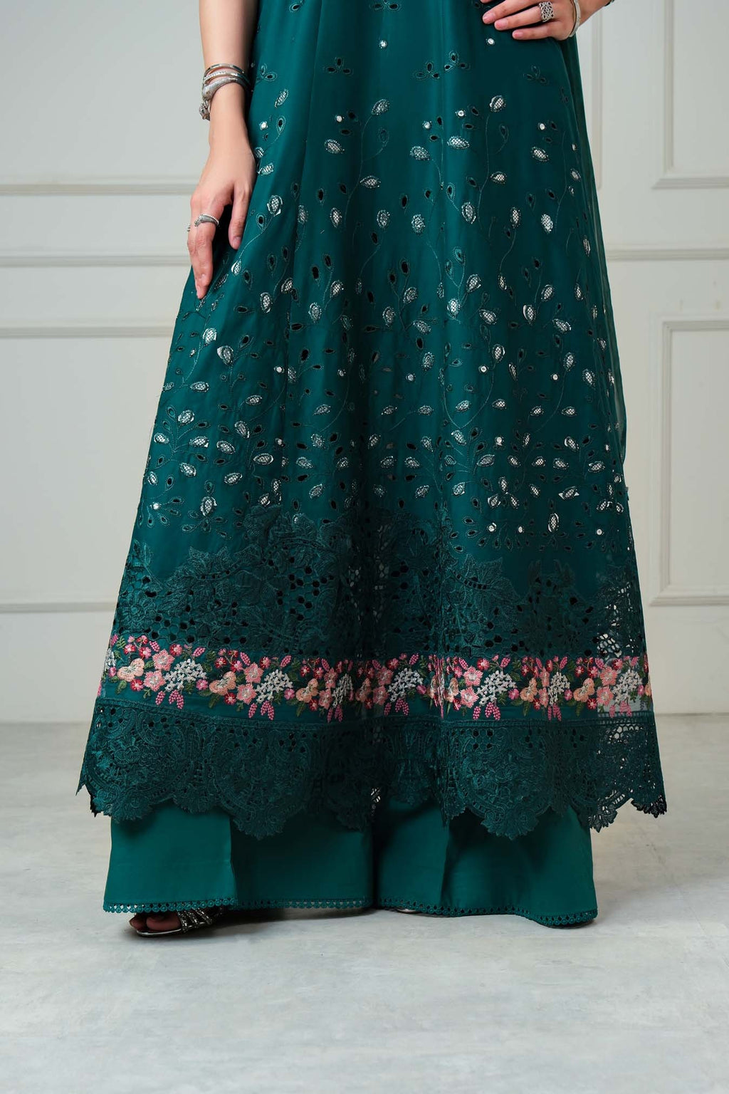 Teal dress with floral embroidery on a plain background