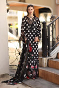 Woman in a long, black and white polka dot dress with floral accents standing on steps.