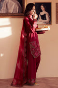 Woman in a red embroidered outfit holding a tray with food in an elegant room.