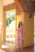 Woman in a pink outfit standing in a doorway with a scenic background