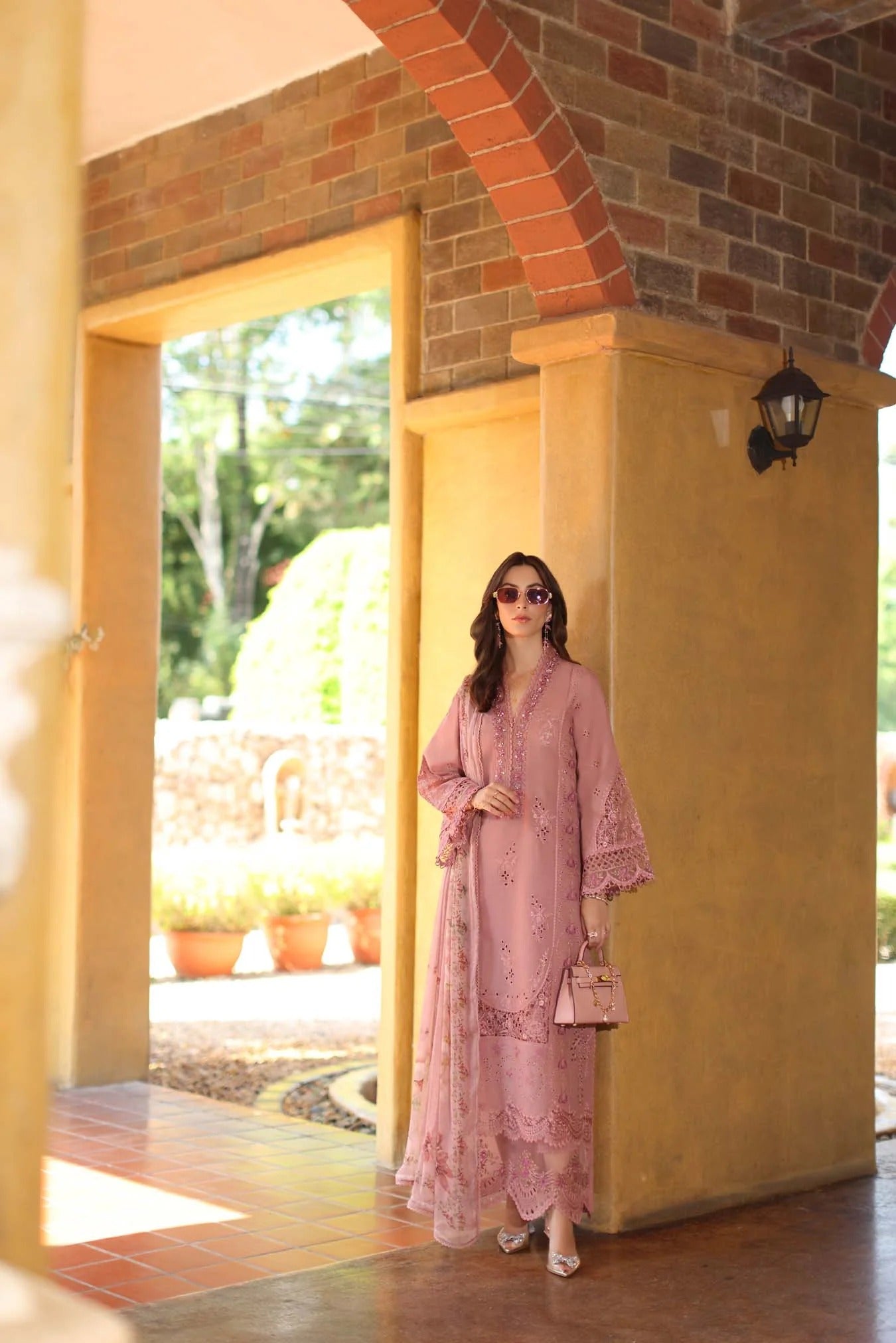 Woman in a pink outfit standing in a doorway with a scenic background