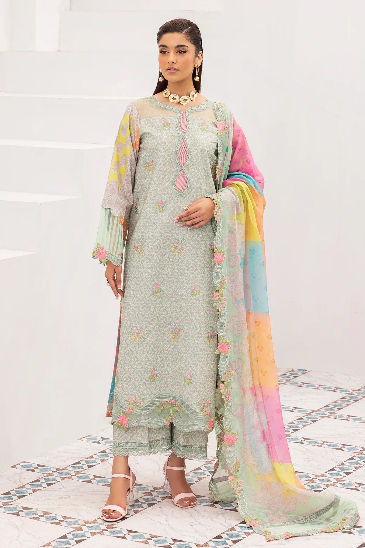 Woman wearing a light green traditional outfit with a colorful dupatta on a white background