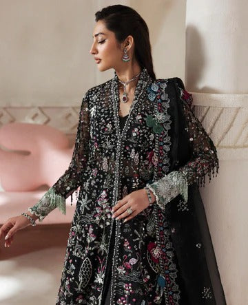Woman wearing a black embroidered outfit with floral patterns in an indoor setting.