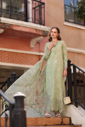 Woman in a light green traditional outfit standing on steps with a building in the background