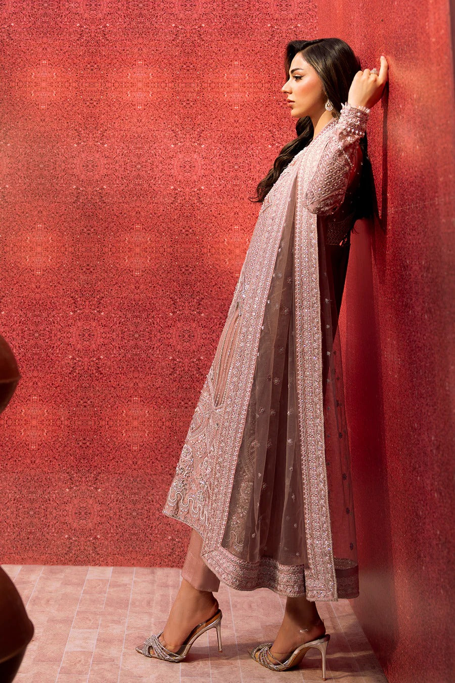 Woman in a traditional outfit against a red wall