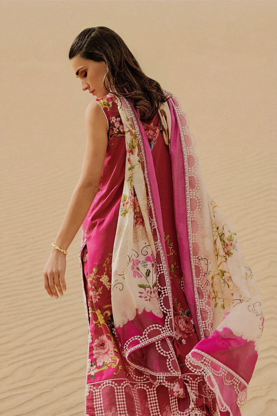 Woman wearing a pink saree with floral patterns against a beige background