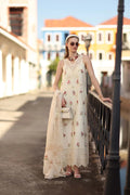 Woman in a floral dress standing on a street with colorful buildings in the background