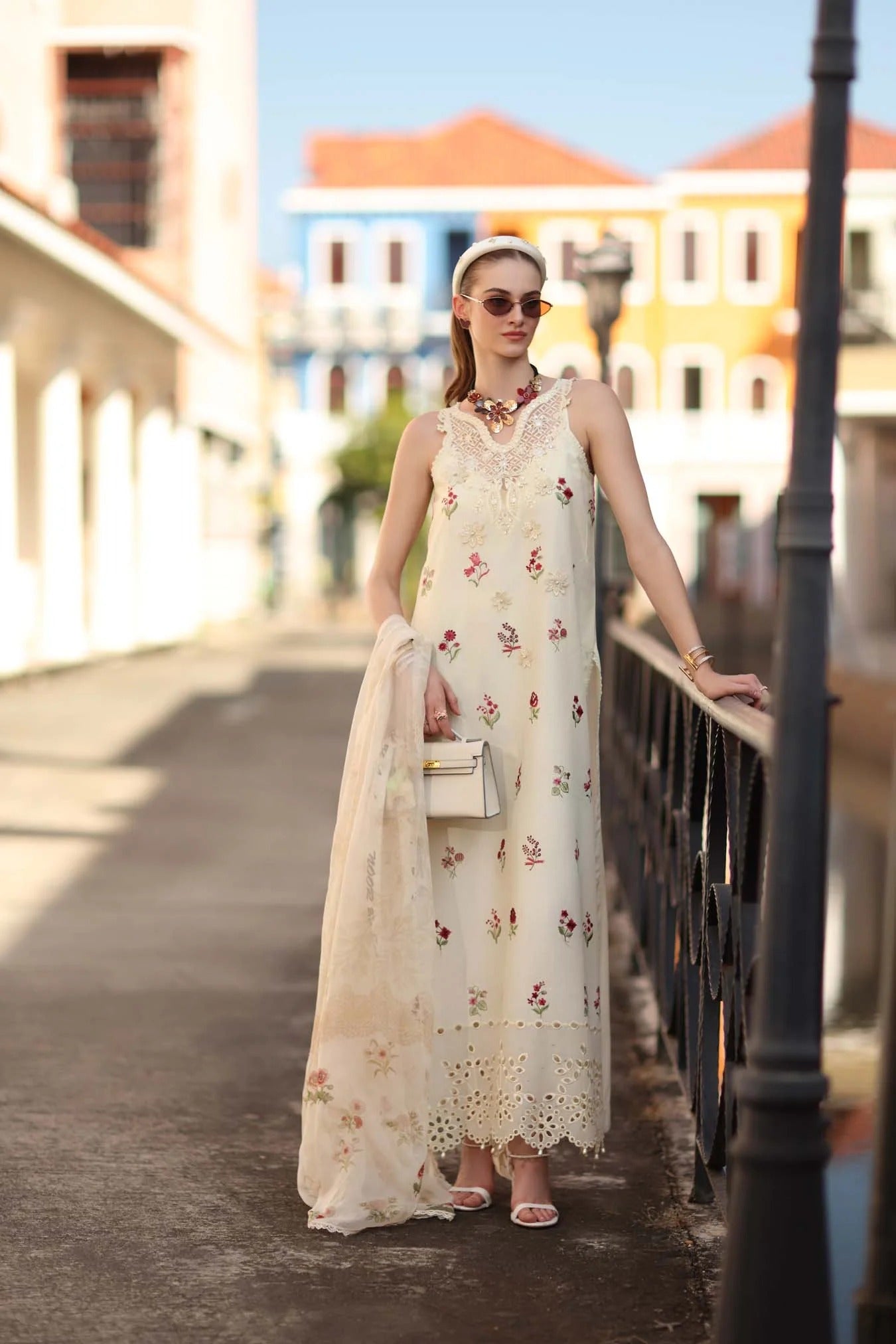 Woman in a floral dress standing on a street with colorful buildings in the background
