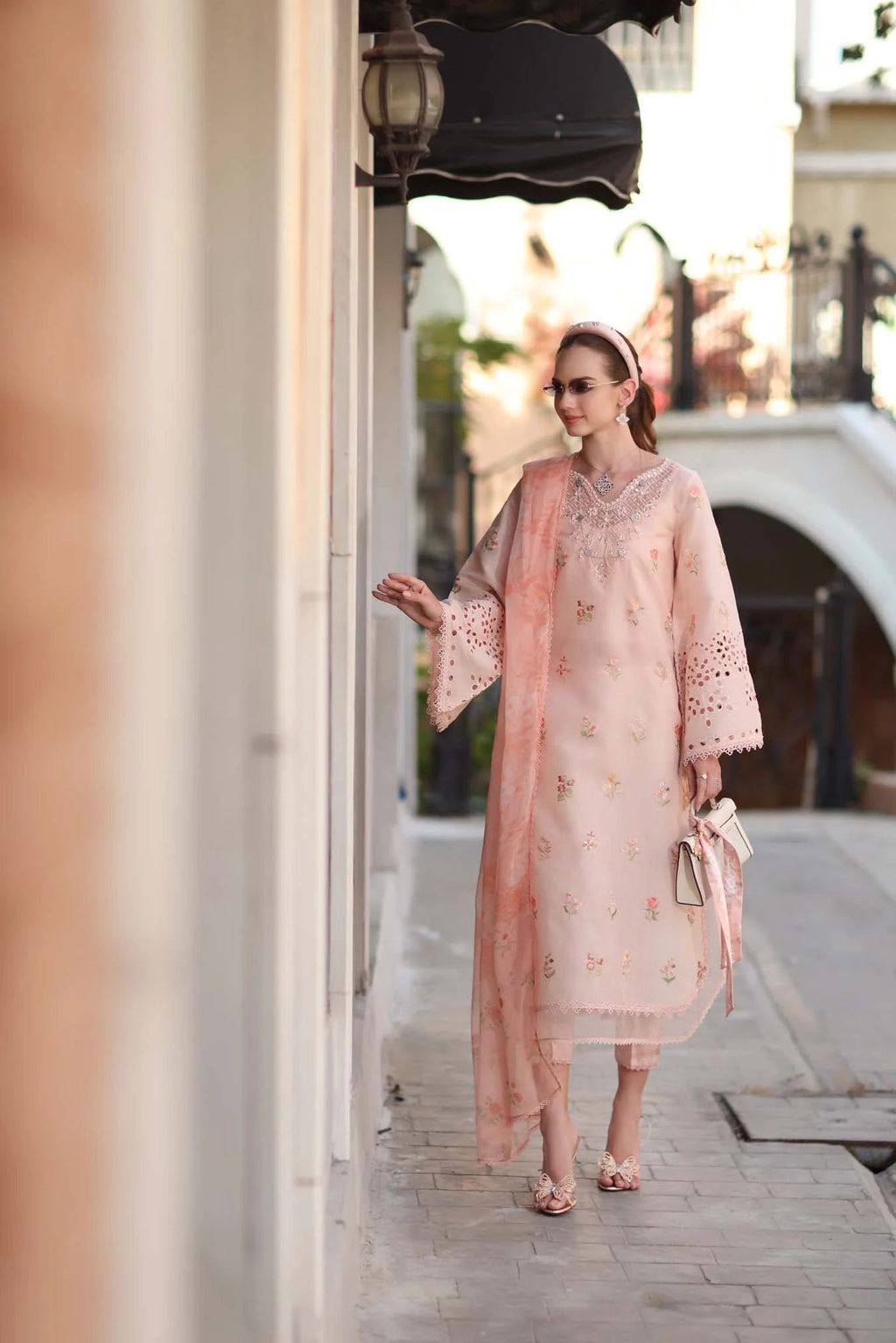 Woman in a light pink dress standing on a street with blurred background