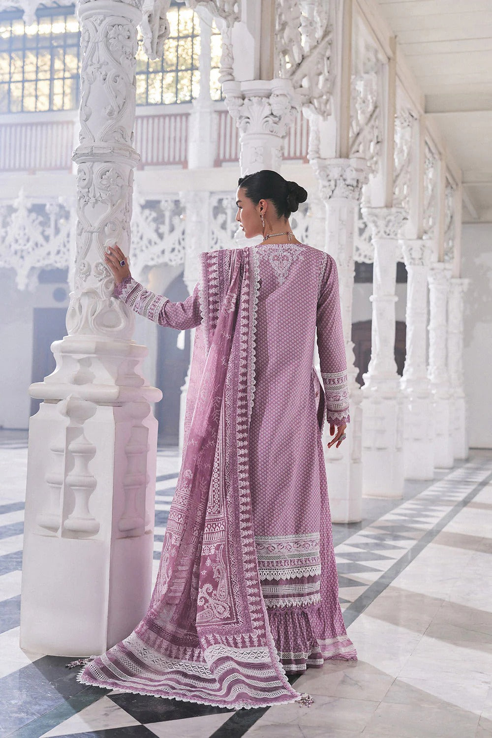 Woman in a pink traditional outfit standing in an ornate white architectural setting