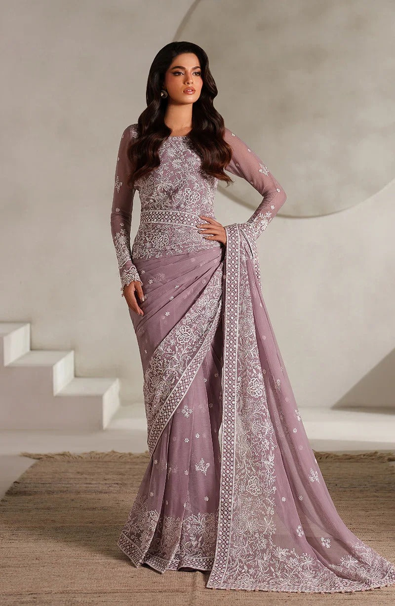 Woman wearing a mauve saree with intricate patterns in a neutral setting