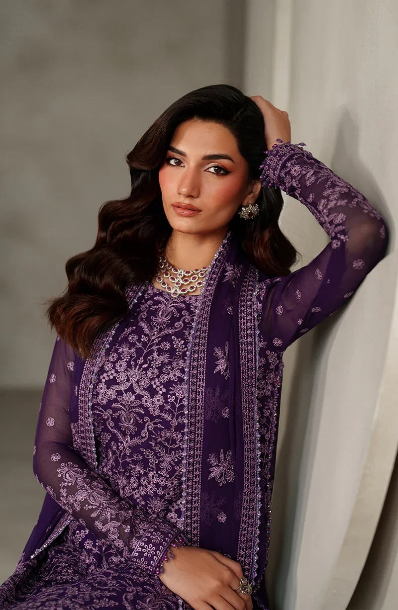 Woman wearing a purple embroidered outfit against a neutral background