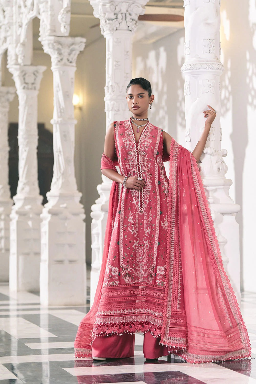 Woman in a pink traditional outfit standing in a white architectural setting