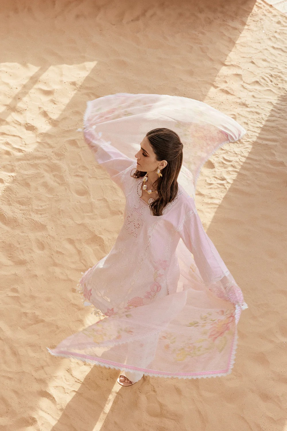 Woman in a flowing dress standing in a desert landscape