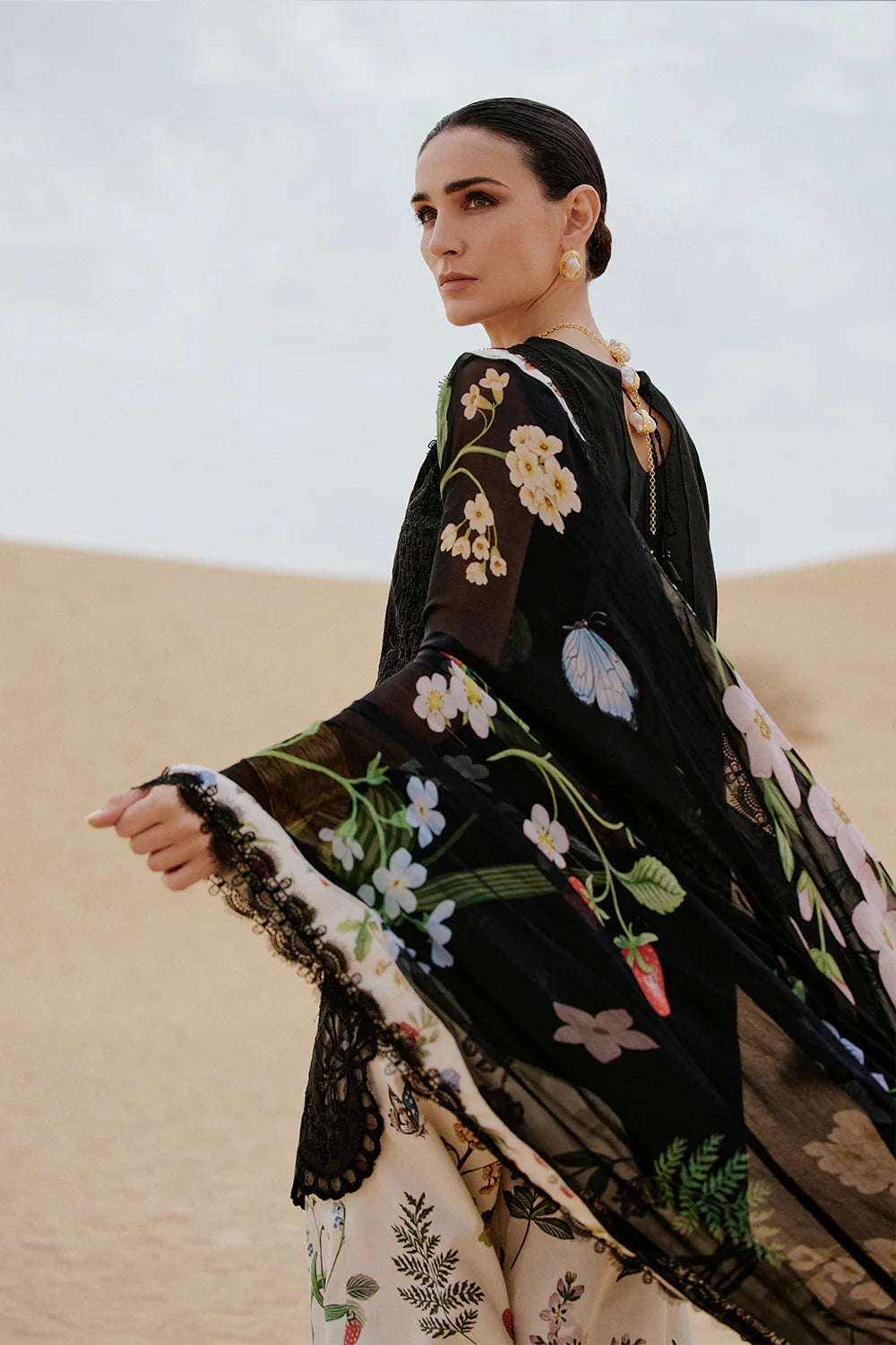 Woman wearing a black embroidered dress in a desert setting