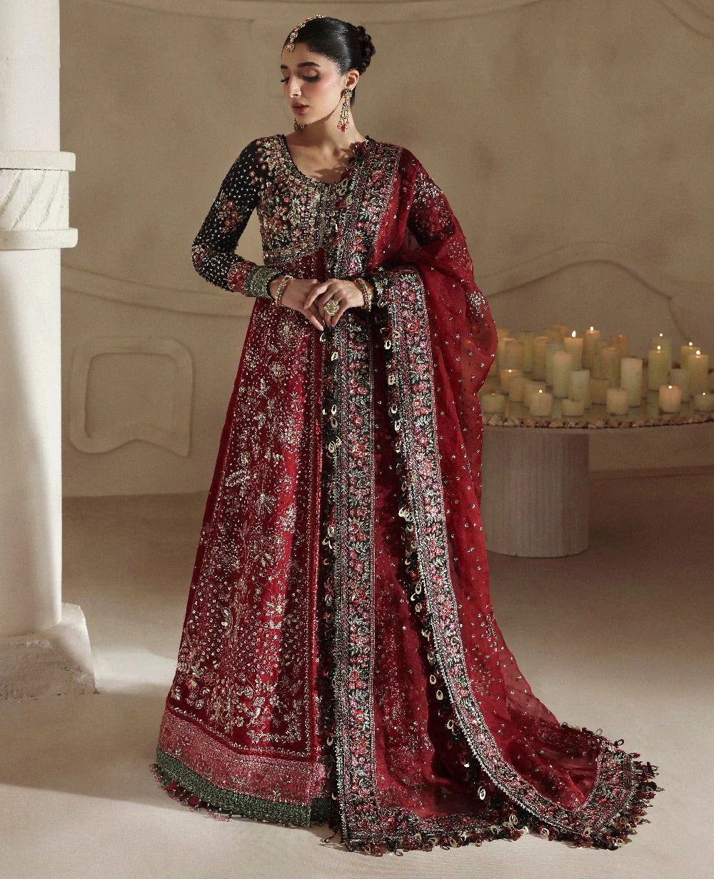 Woman in a red and black embroidered traditional outfit standing in a softly lit room.