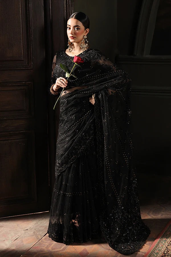 Woman in a black saree holding a red rose against a dark background