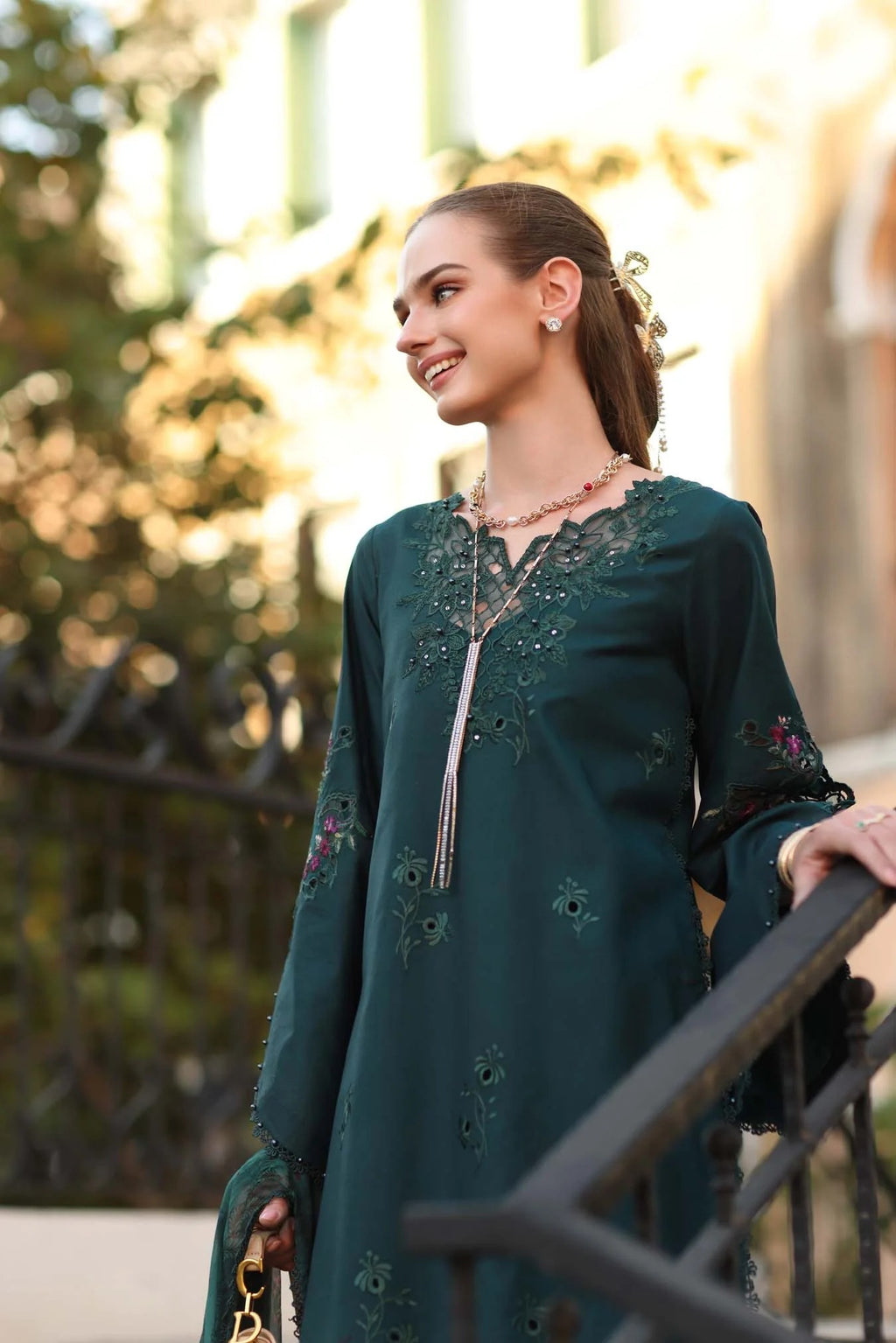 Woman wearing a green embroidered dress with a blurred natural background