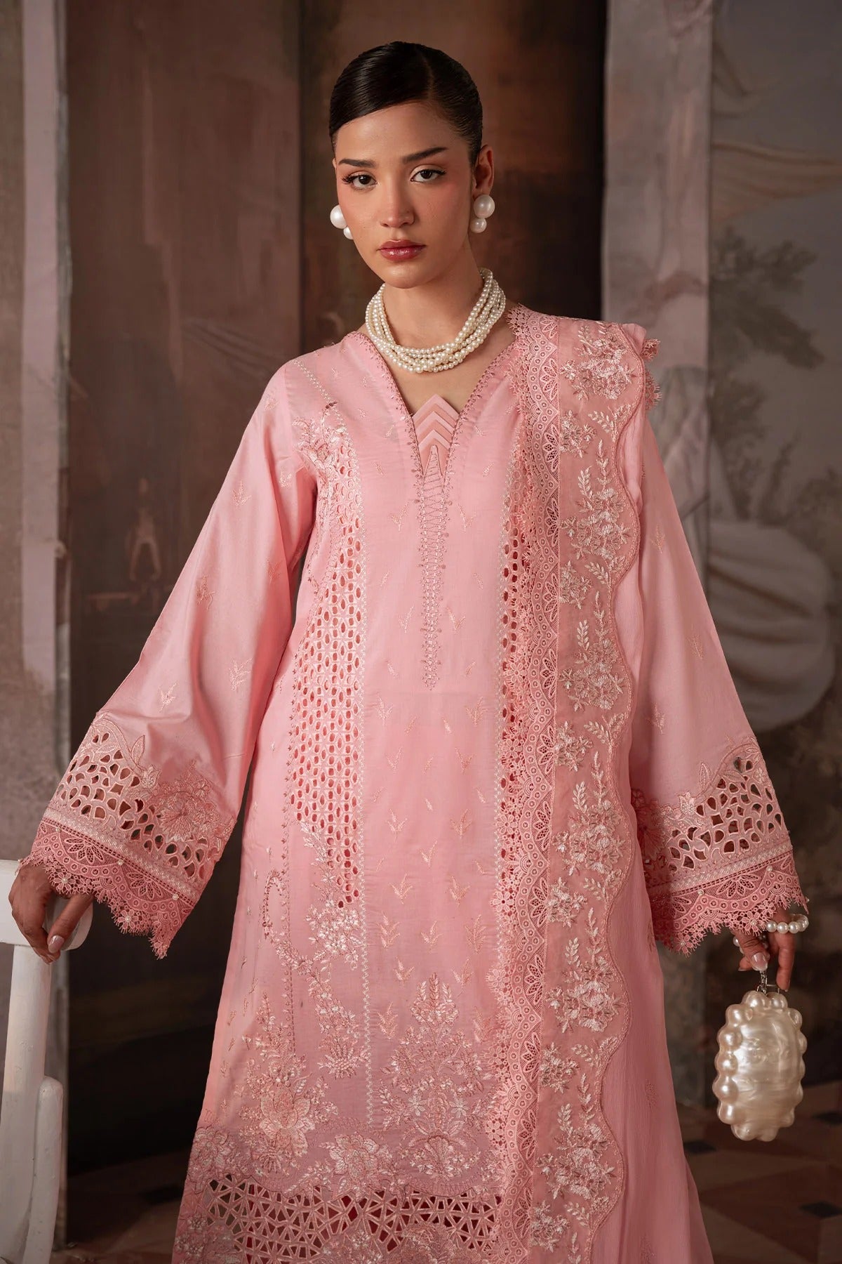Woman wearing a pink embroidered dress with intricate detailing.
