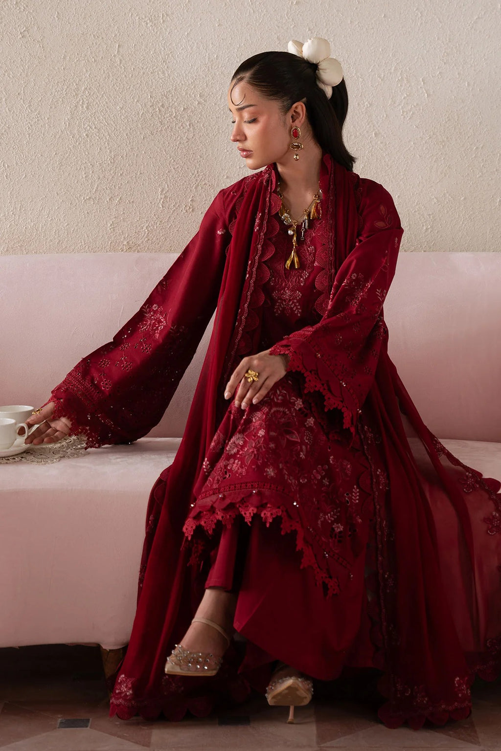 Woman in a red traditional outfit sitting on a pink couch.
