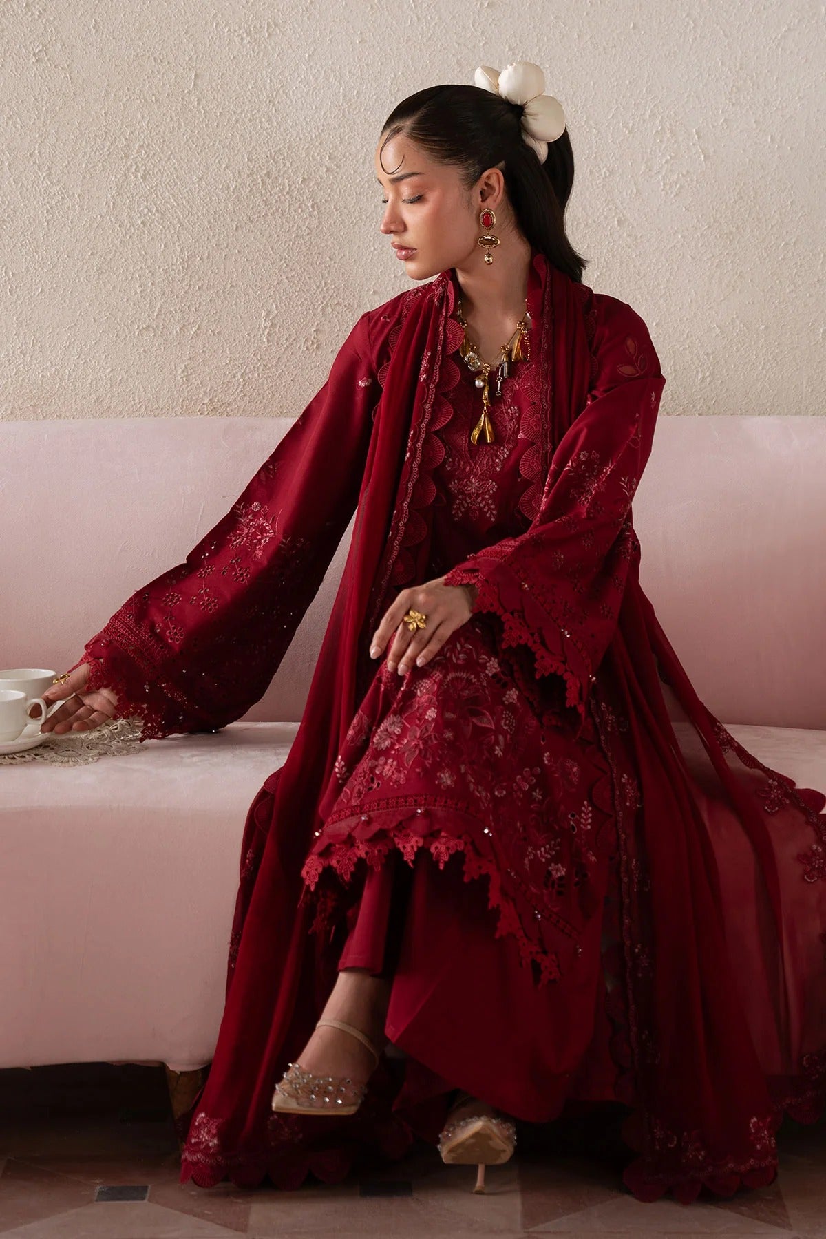 Woman in a red traditional outfit sitting on a pink couch.