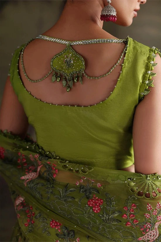 Close-up back view of a woman wearing a bright olive green embellished blouse with a decorative chain necklace and a matching embroidered dupatta.