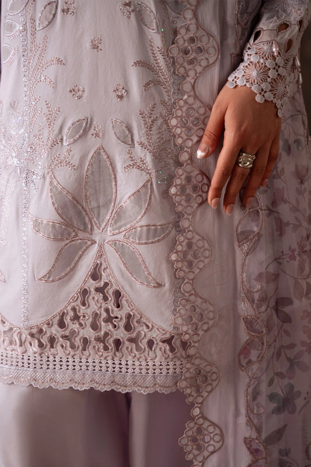 Close-up of a hand holding a piece of embroidered fabric with intricate patterns.