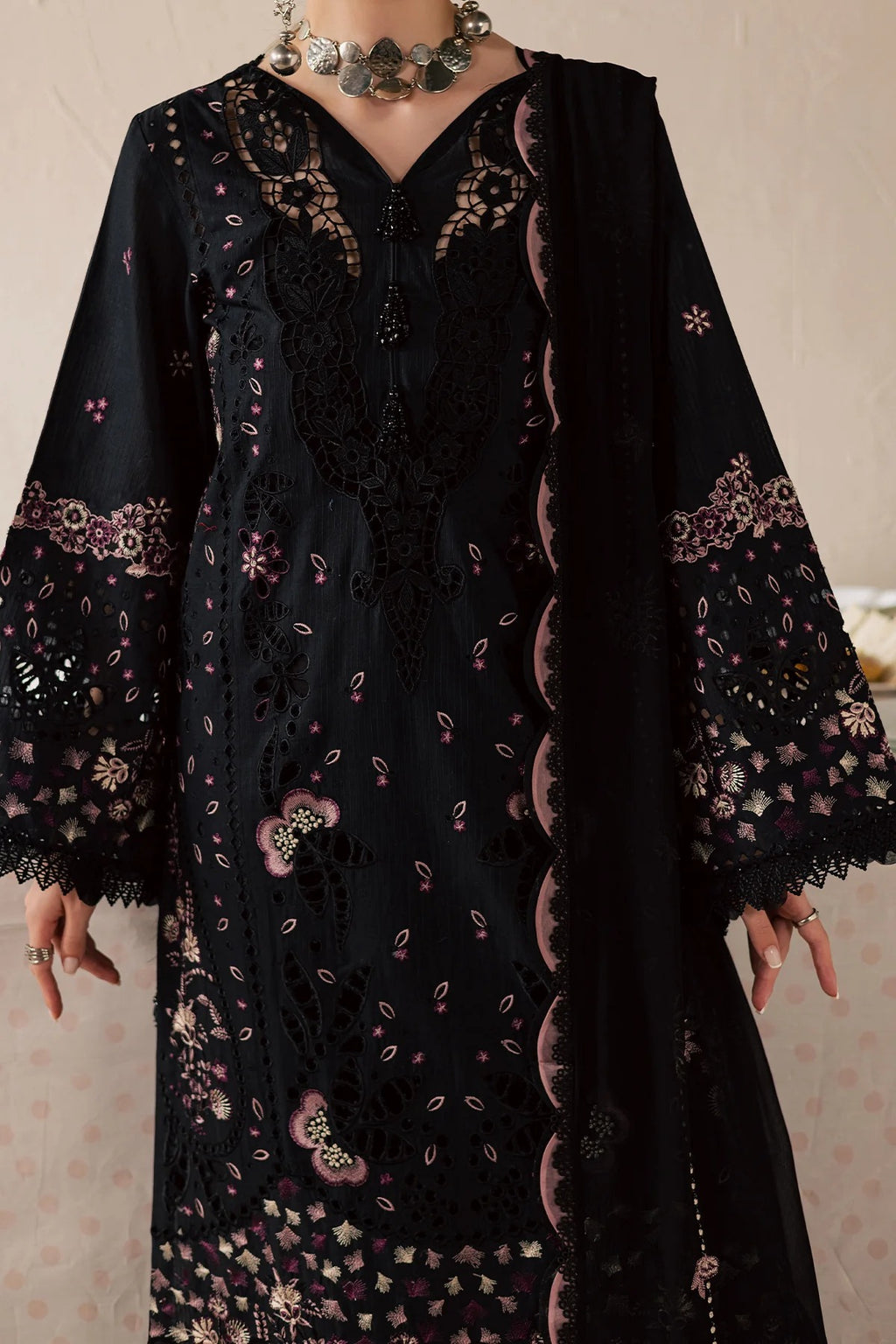 Black embroidered dress with floral patterns on a neutral background
