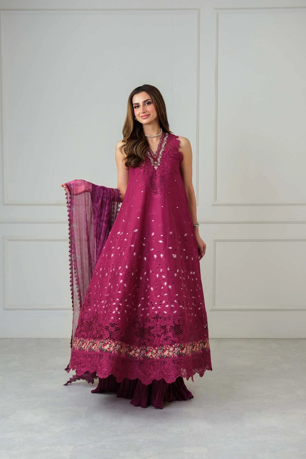 Woman wearing a magenta traditional outfit with a matching dupatta against a white background
