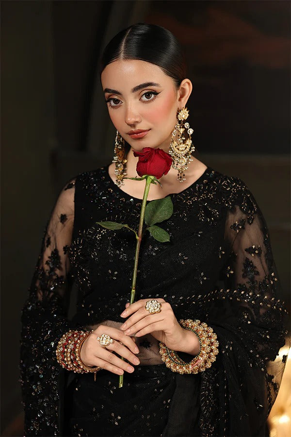 Woman in a black outfit holding a red rose against a dark background