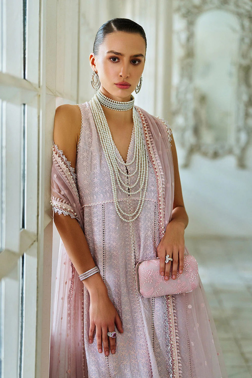 Woman in a pink dress with jewelry and a clutch in an elegant setting