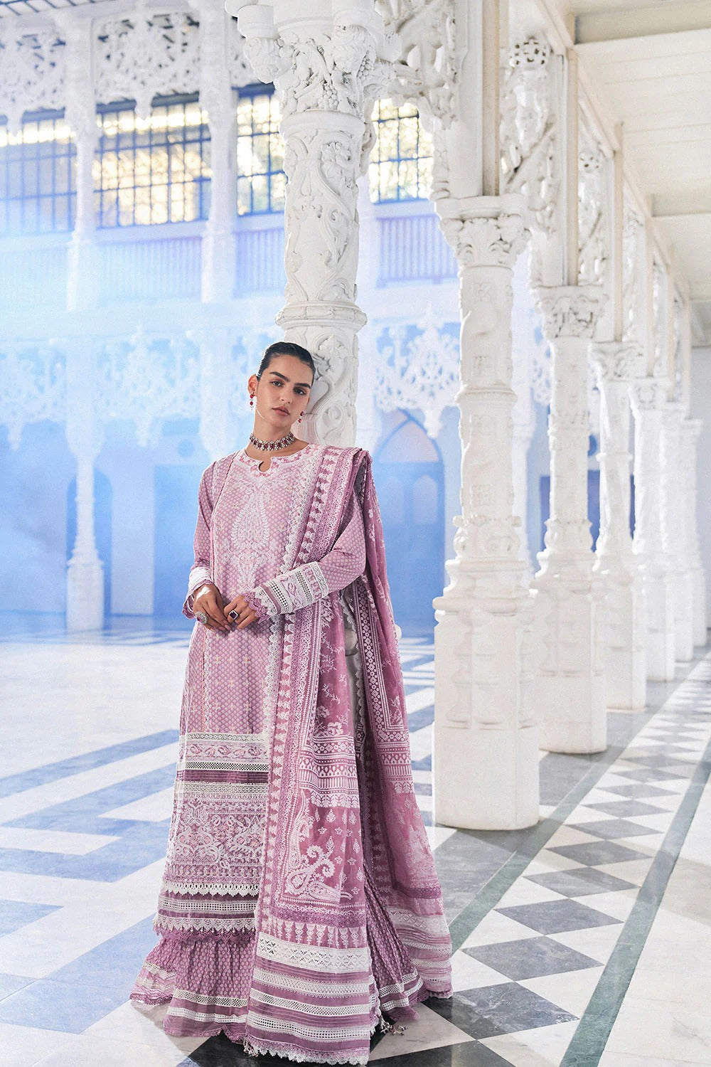 Woman in a pink traditional outfit standing in a white architectural setting