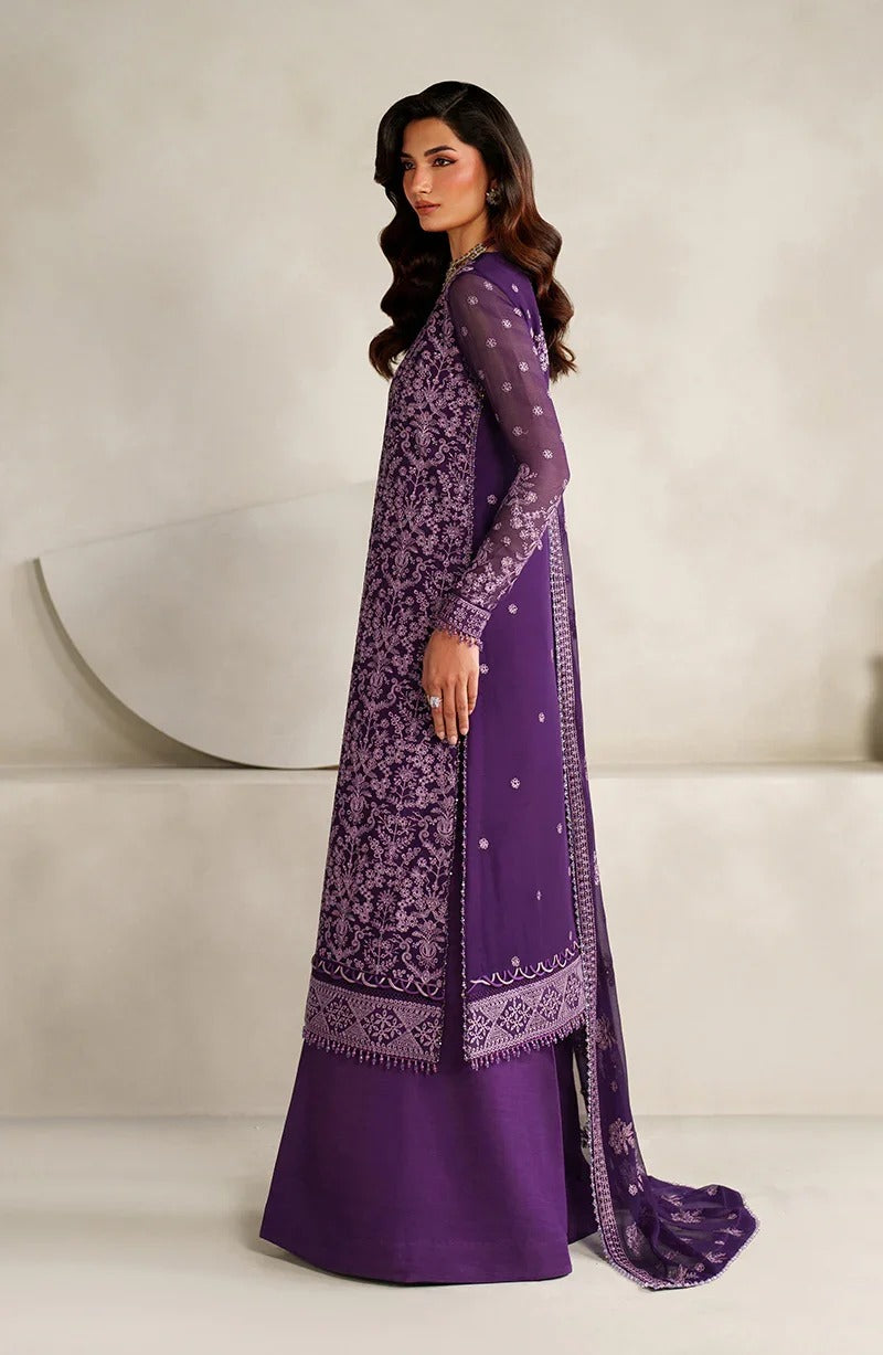 Woman wearing a purple embroidered traditional outfit against a neutral background
