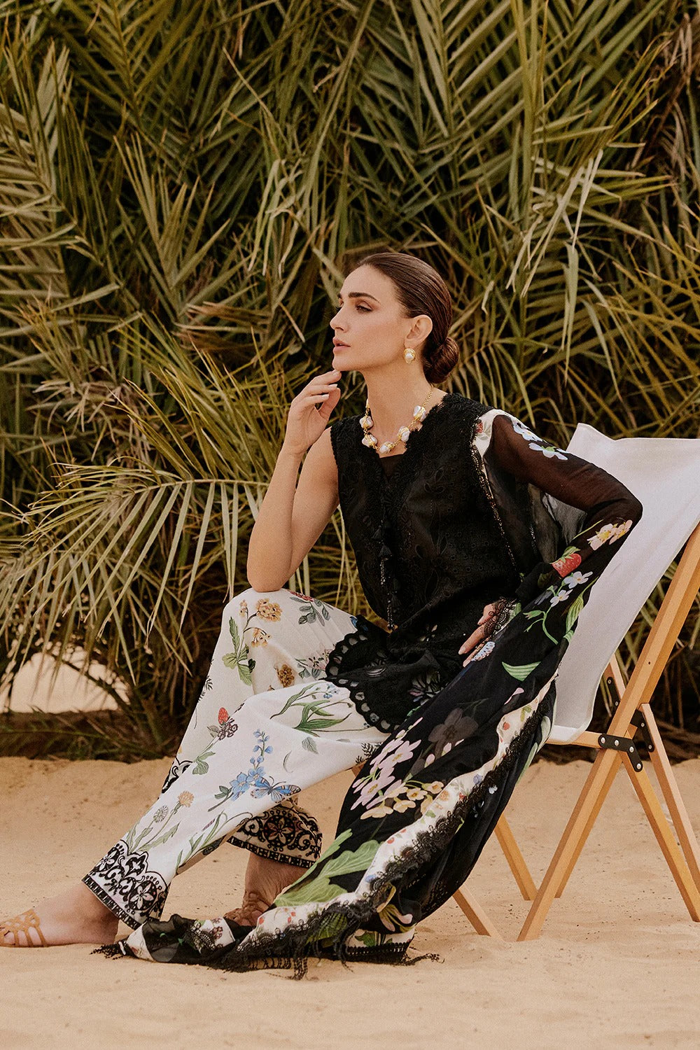 Woman sitting on a chair with a floral skirt and black top in a natural setting