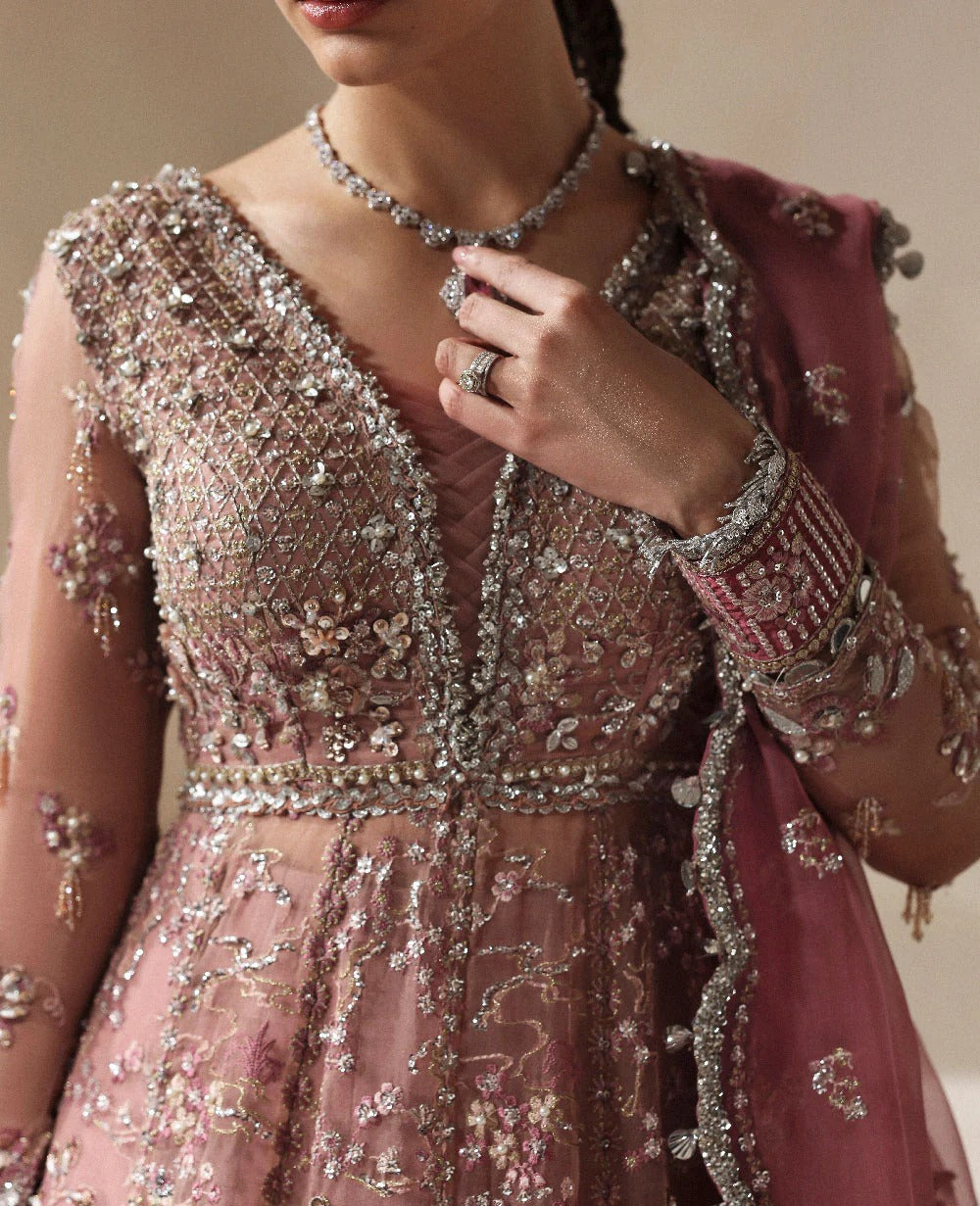 Close-up of a person wearing an intricately designed pink and silver outfit with jewelry.