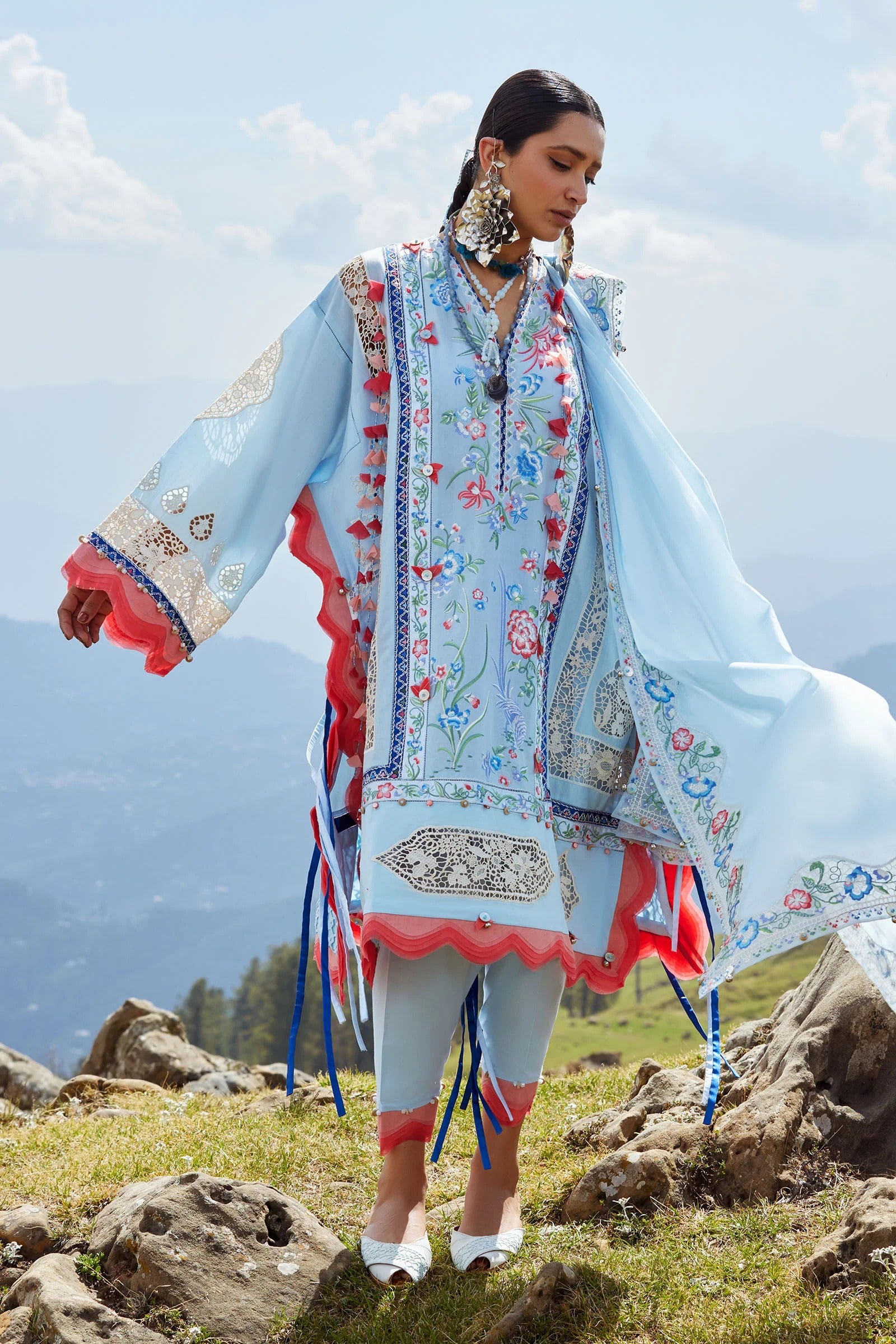 Woman in traditional embroidered outfit standing on a mountainous landscape