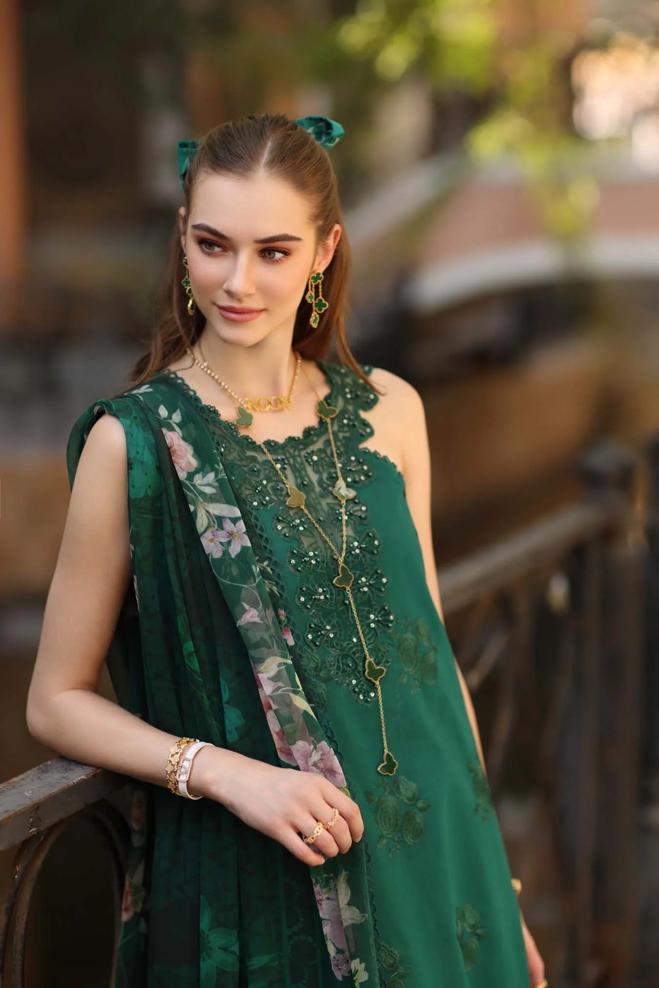 Woman in a green dress with floral details standing outdoors.