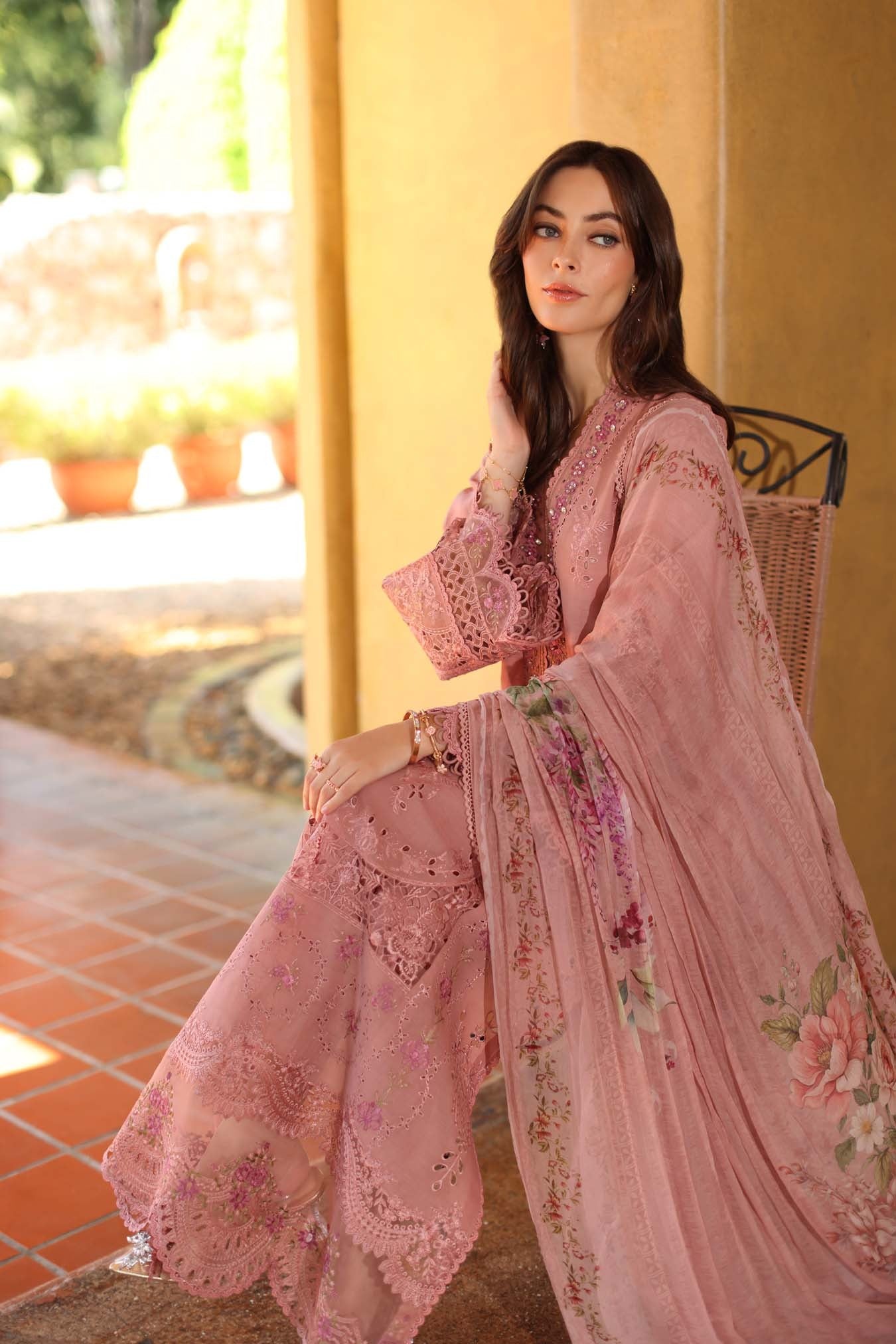 Woman wearing a pink embroidered outfit sitting outdoors.