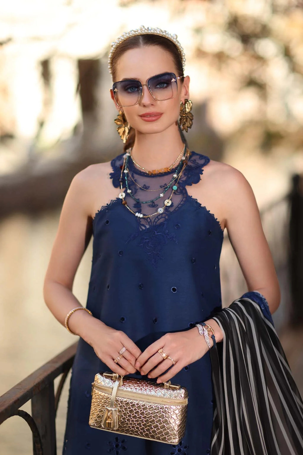 Woman in a blue dress holding a gold handbag with a blurred background